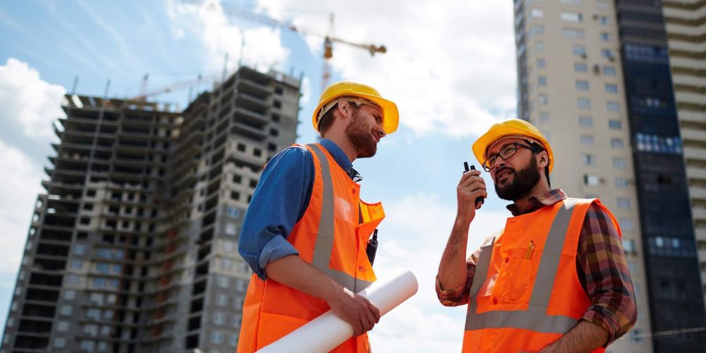 Contractor speaking on walkie-talkie with co-worker near by